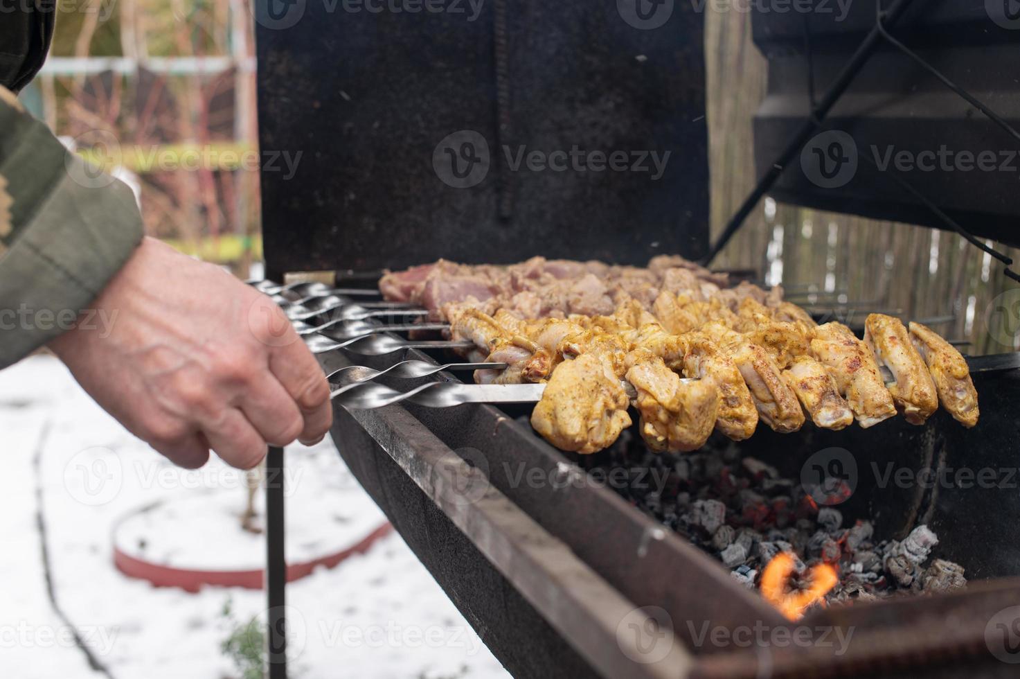 en man vänder en kött kebab på de grill, utegrill foto