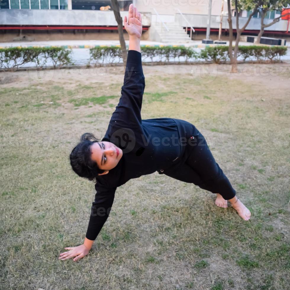 ung indisk kvinna praktiserande yoga utomhus- i en parkera. skön flicka öva grundläggande yoga utgör. stillhet och koppla av, kvinna lycka. grundläggande yoga poser utomhus- foto