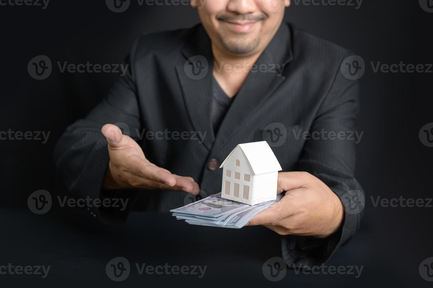 papper hus och pengar på en försäljare hand på svart bakgrund, foto