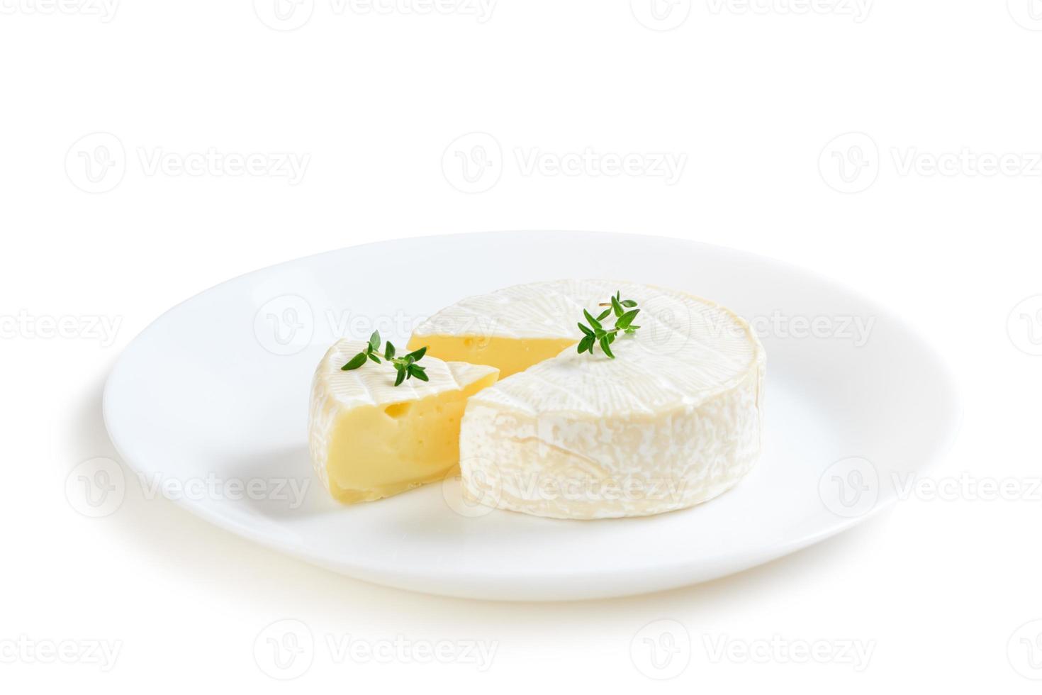 Camembert ost med timjan på vit maträtt och isolerat på vit bakgrund. foto