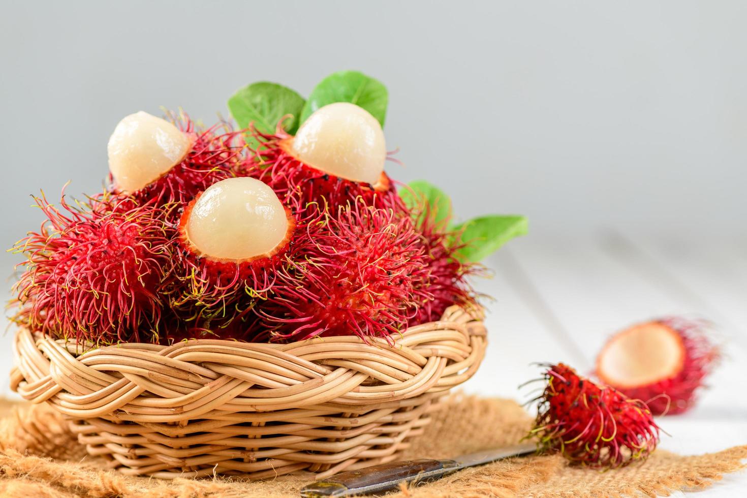 färsk rambutan frukt med löv i bambu korg på trä bakgrund. foto