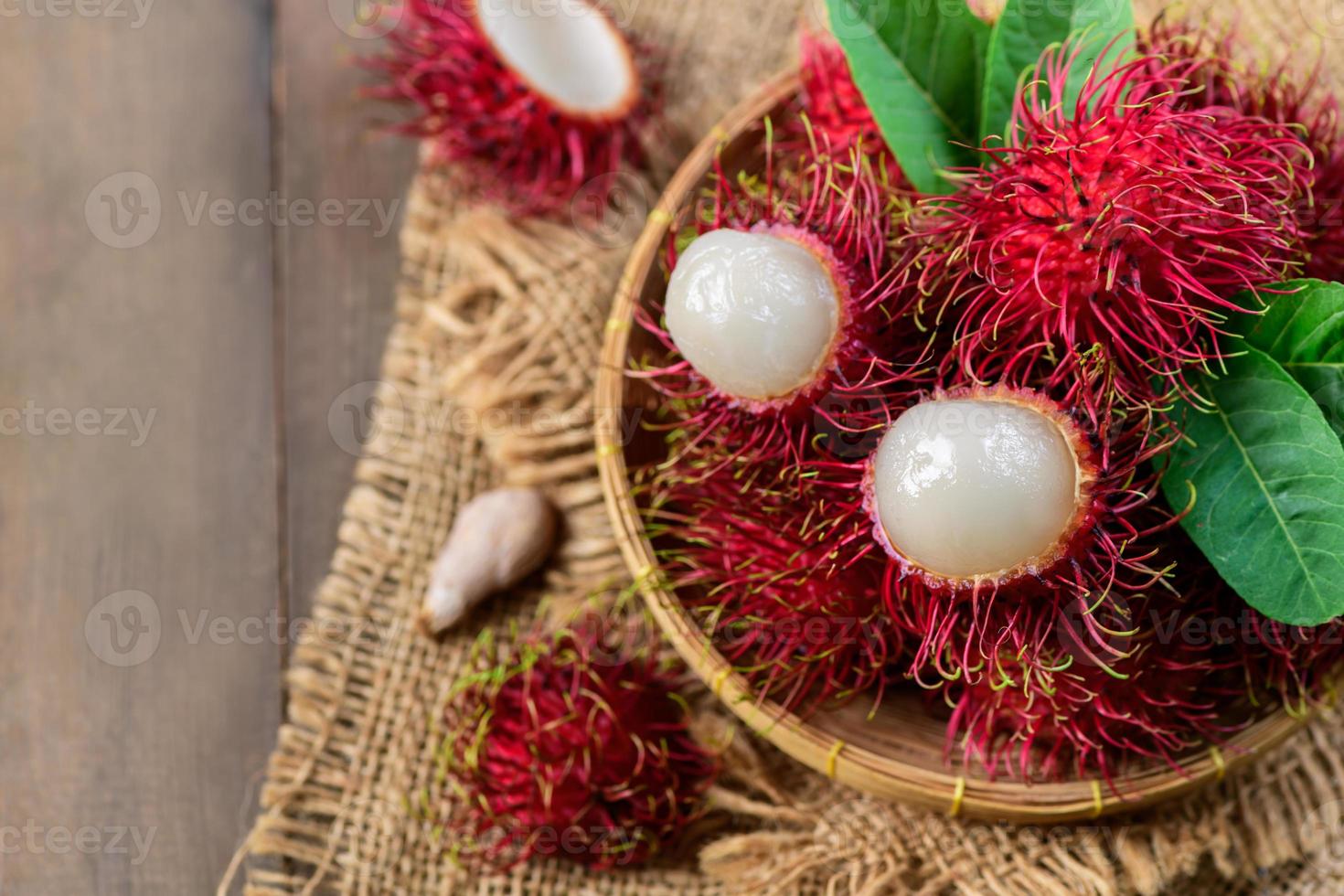 topp se av färsk rambutan frukt med löv på bambu korg foto