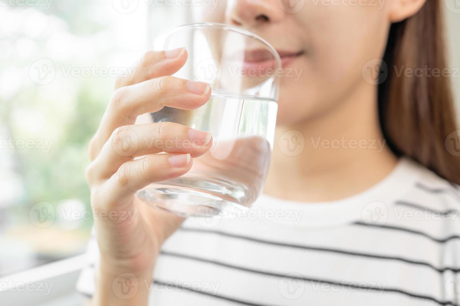 Lycklig skön, asiatisk ung kvinna, flicka dricka, smutta färsk glas av vatten för hydratisering av kropp, innehav transparent glas i henne hand, törstig på Hem. hälsa vård, friska livsstil begrepp. foto