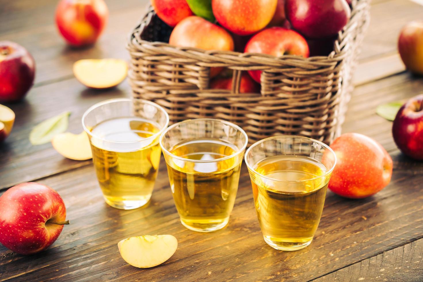 äppeljuice i glas och äpplen i korgen foto