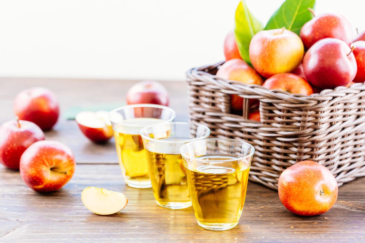 äppeljuice i glas och äpplen i korgen foto