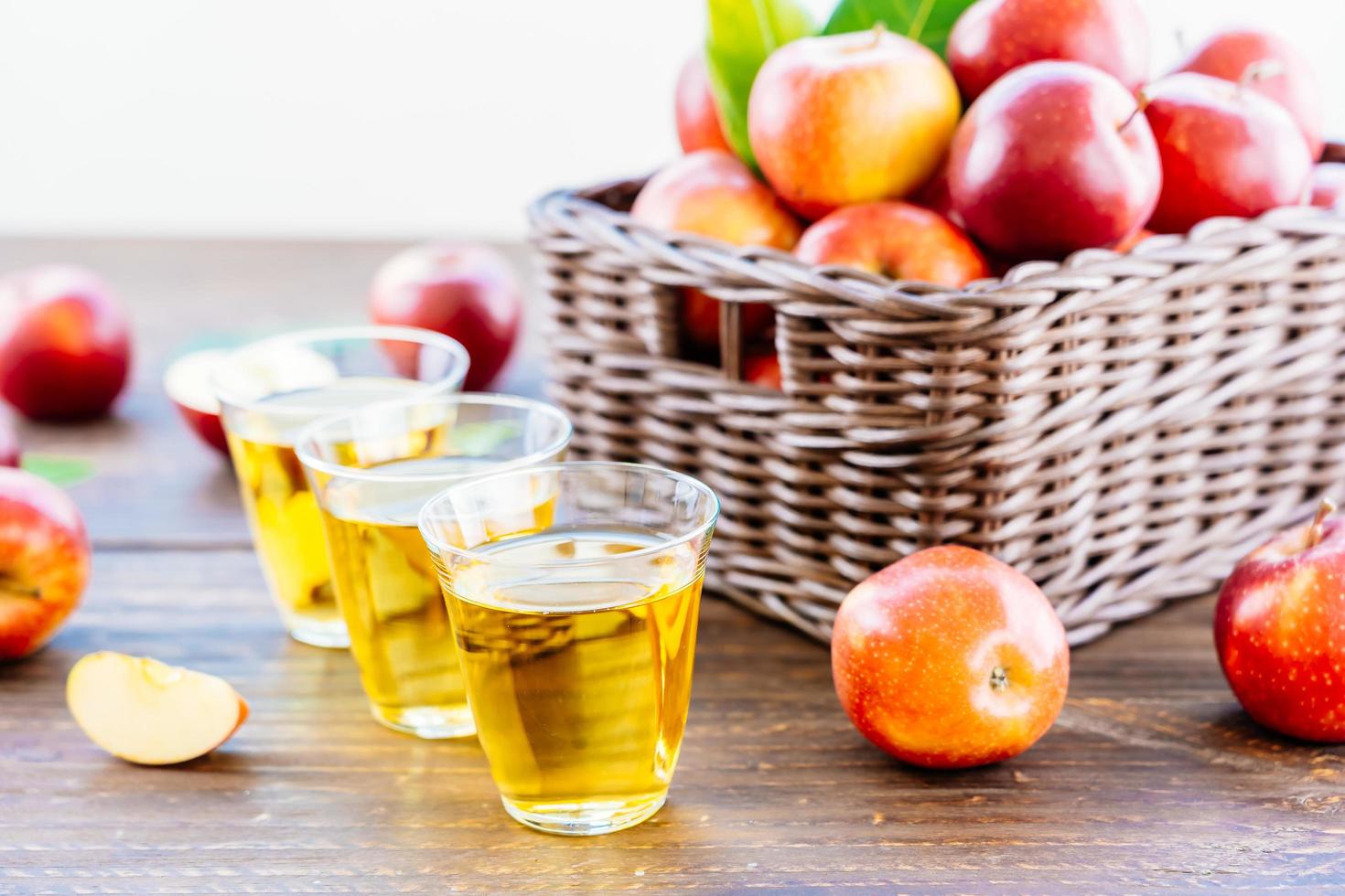 äppeljuice i glas och äpplen i korgen foto