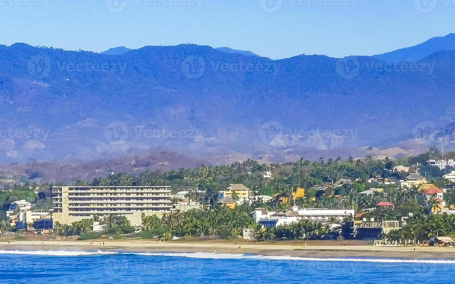 Sol strand klippor stenar vågor palmer bergen puerto escondido Mexiko. foto