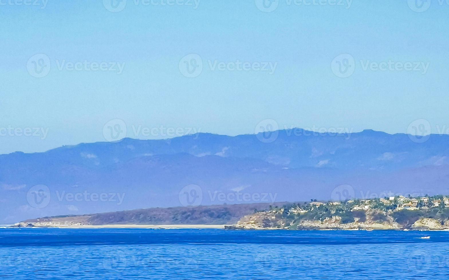 Sol strand klippor stenar vågor palmer bergen puerto escondido Mexiko. foto