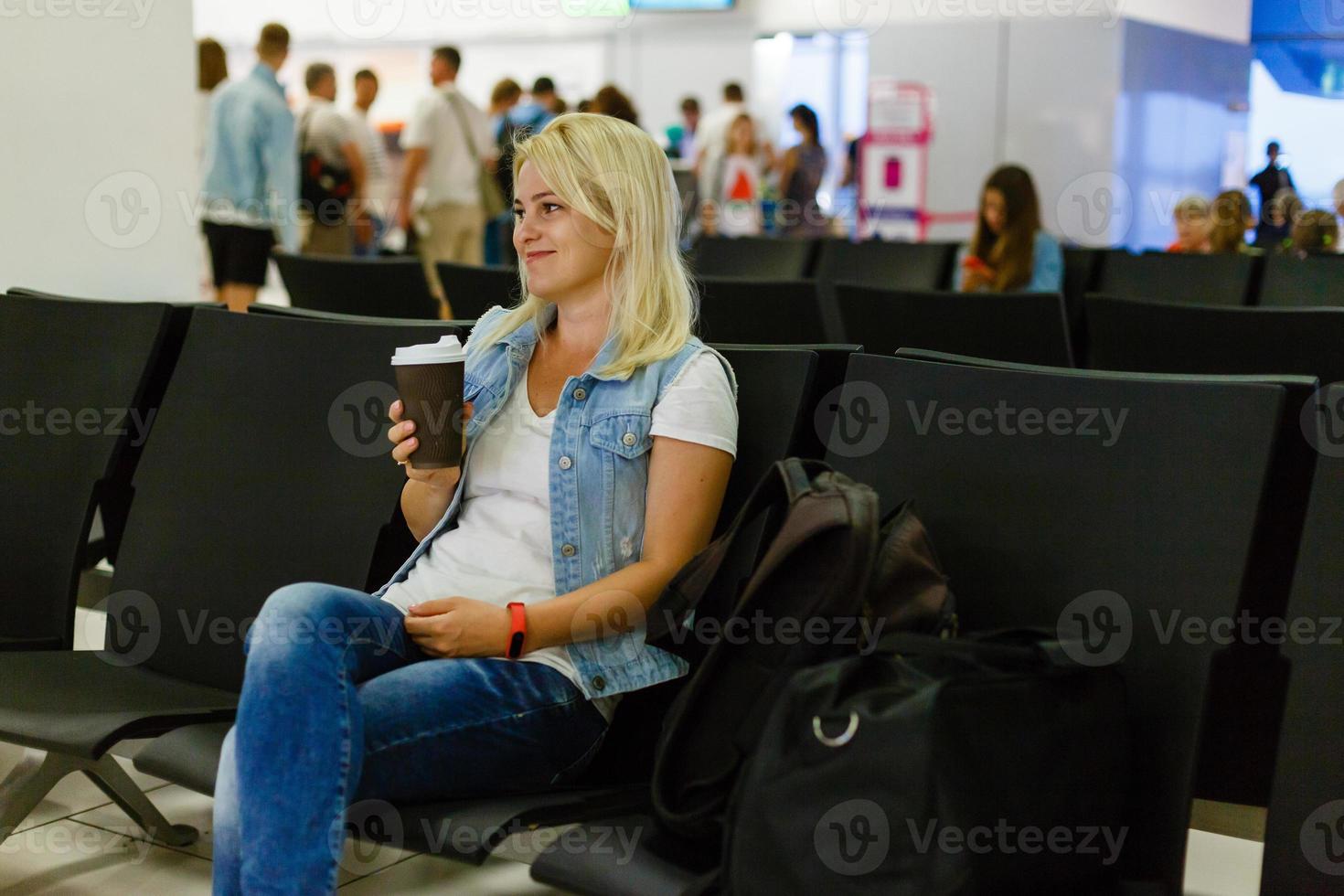 ung kvinna passagerare på de flygplats väntar för henne flyg foto