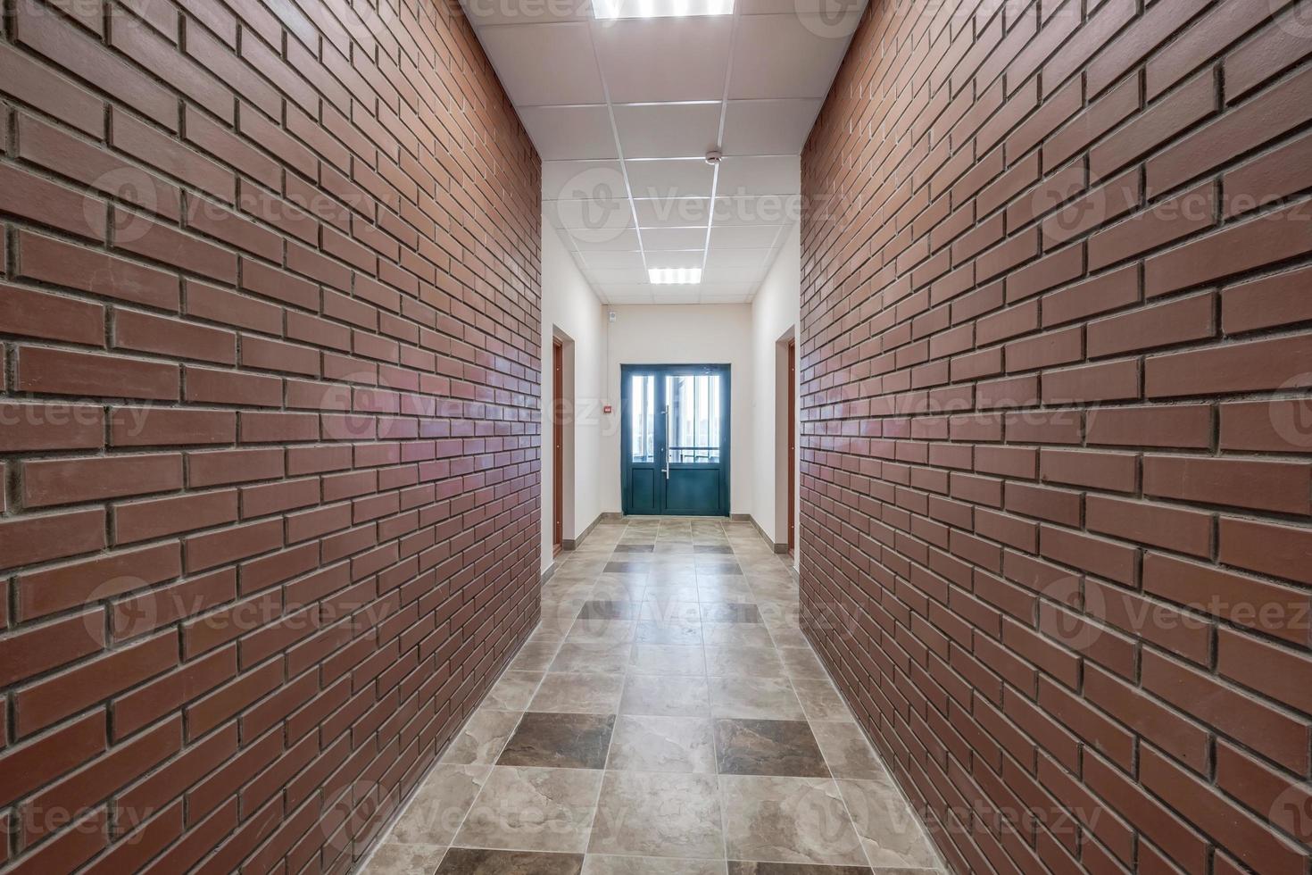 vit tömma lång korridor med röd tegel väggar i interiör av modern lägenheter, kontor eller klinik foto
