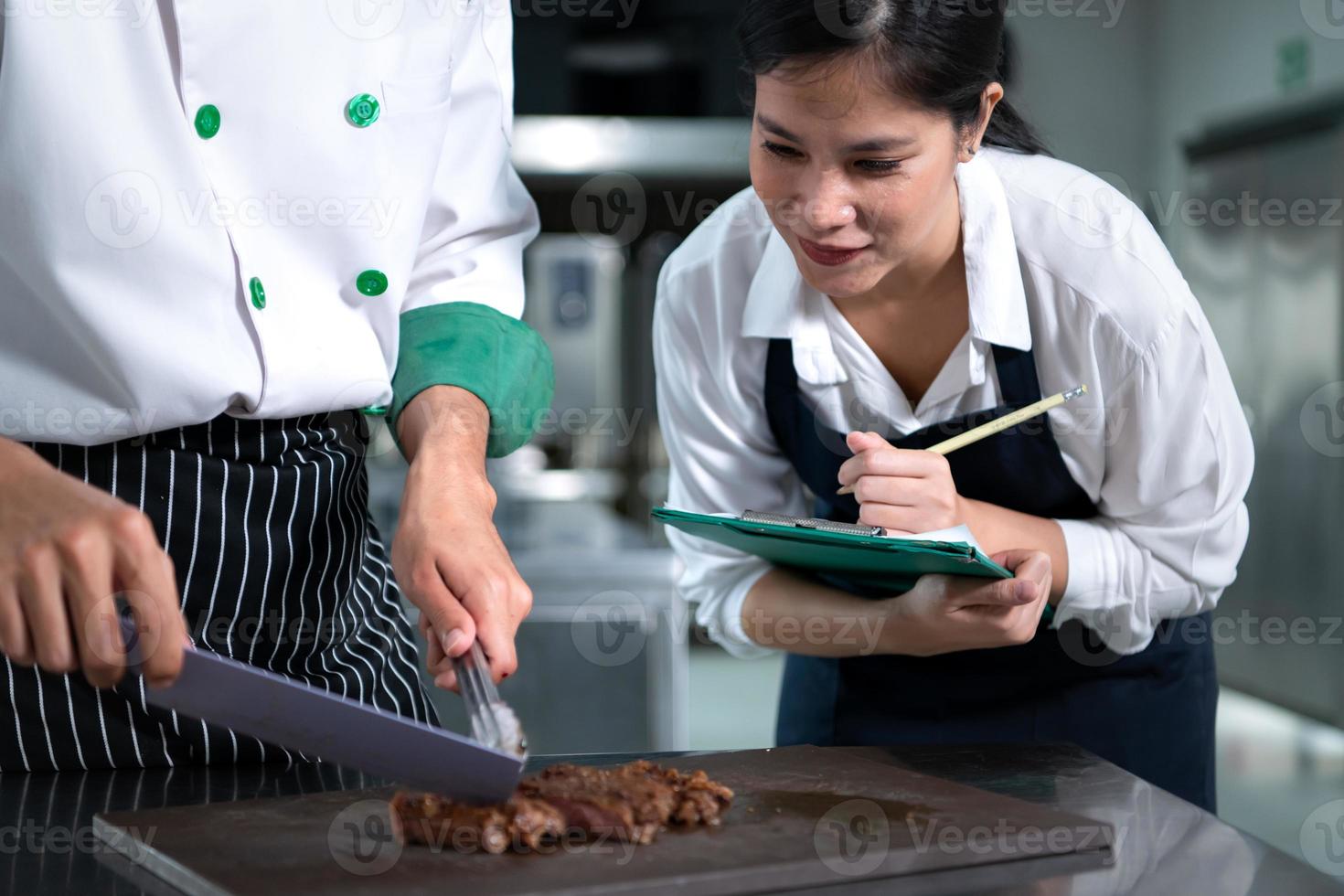 studerande matlagning lärling ta anteckningar på varje steg som de kock kockar i de kulinariska akademins kök. foto