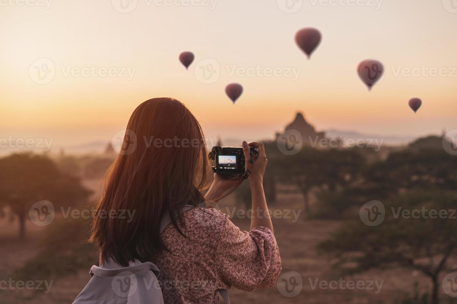 ung kvinna resande njuter med ballonger över gammal pagod på bagan, myanmar på soluppgång foto