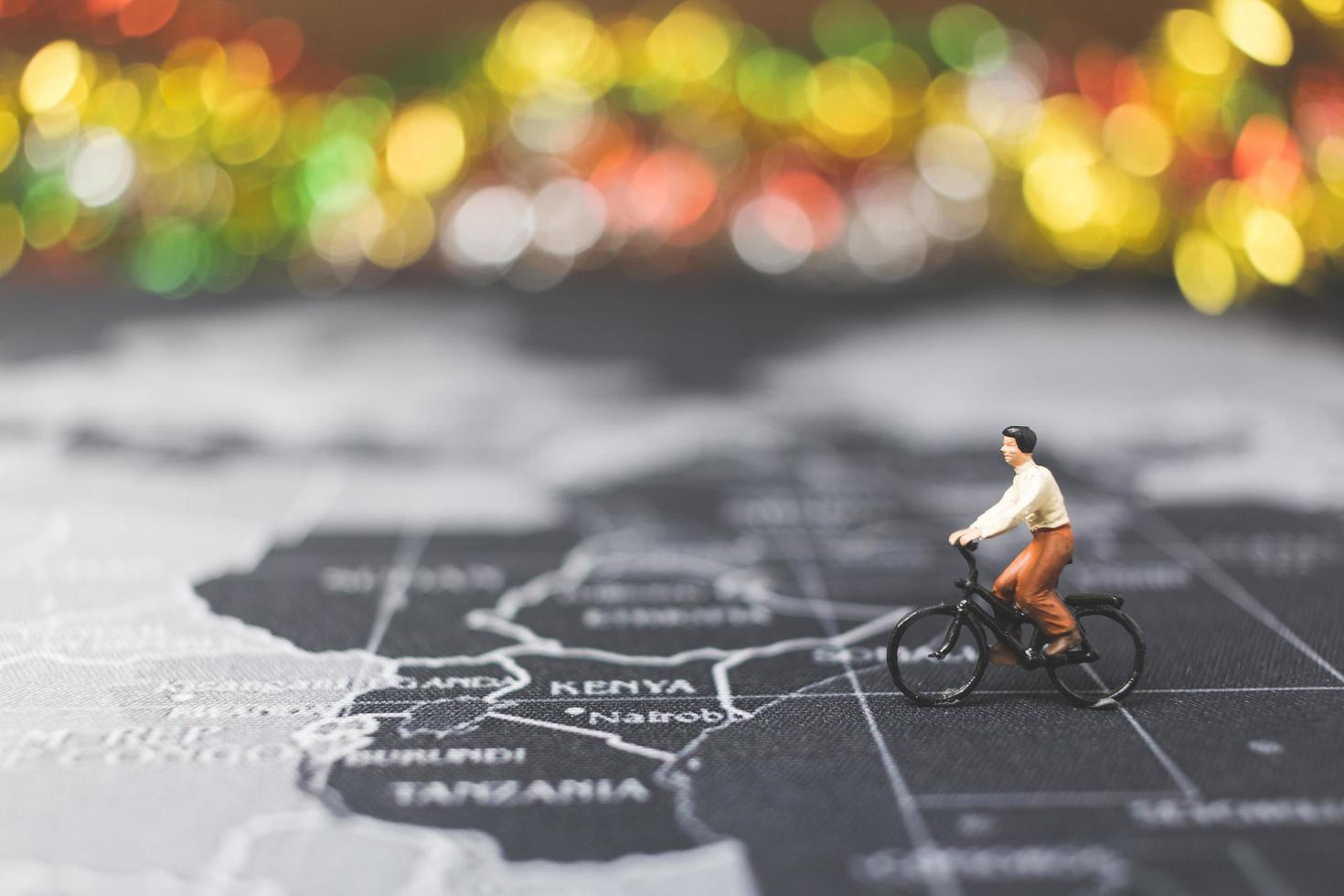 miniatyr resenär som cyklar på en världskarta, reser och utforskar världskonceptet foto