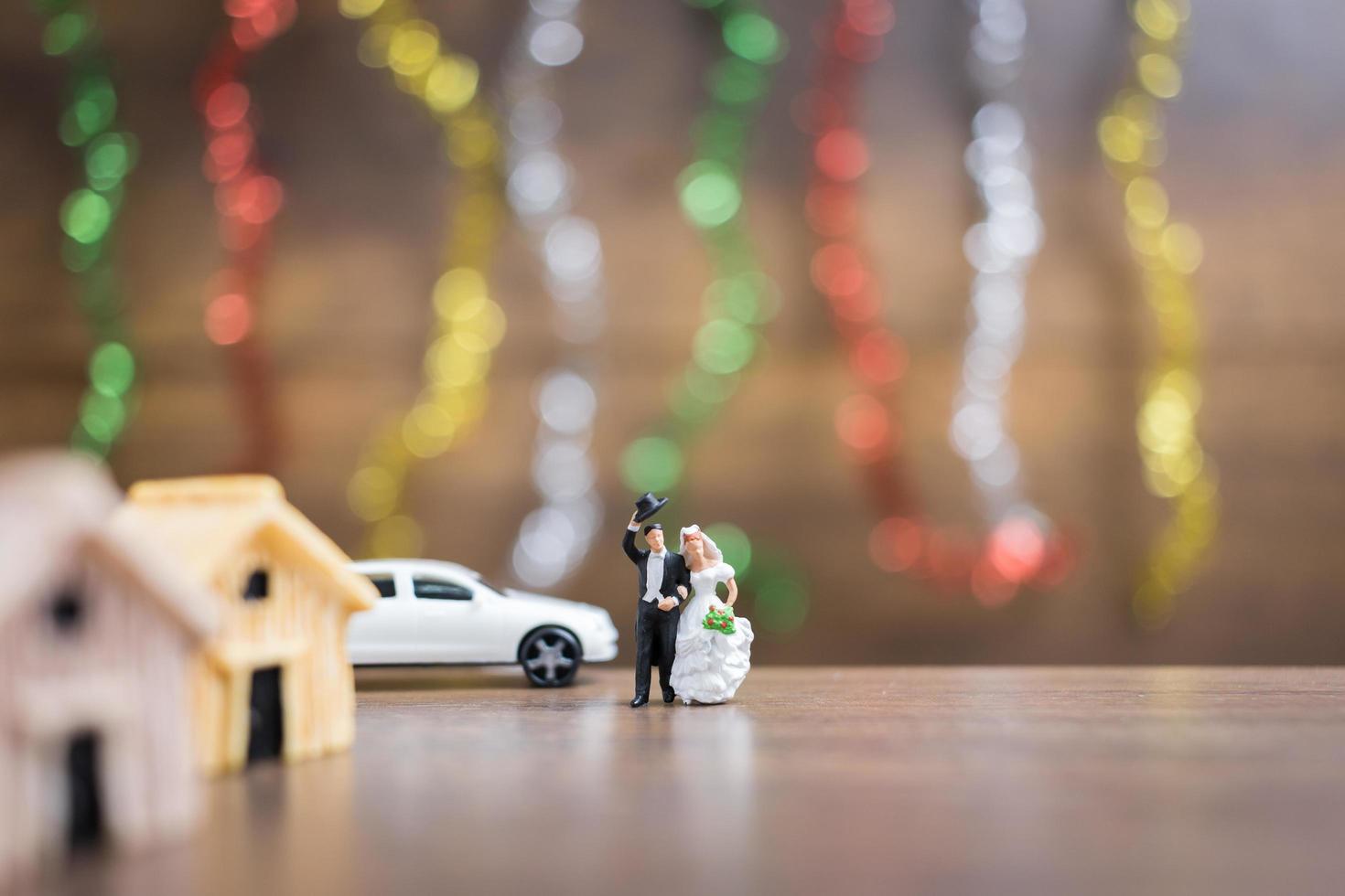 miniatyrbrud och brudgum på ett trägolv med färgglad bokehbakgrund, framgångsrikt familjekoncept foto