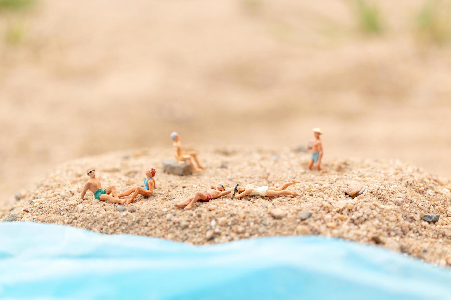miniatyrfolk som bär baddräkter som kopplar av på en strand, sommarbegrepp foto