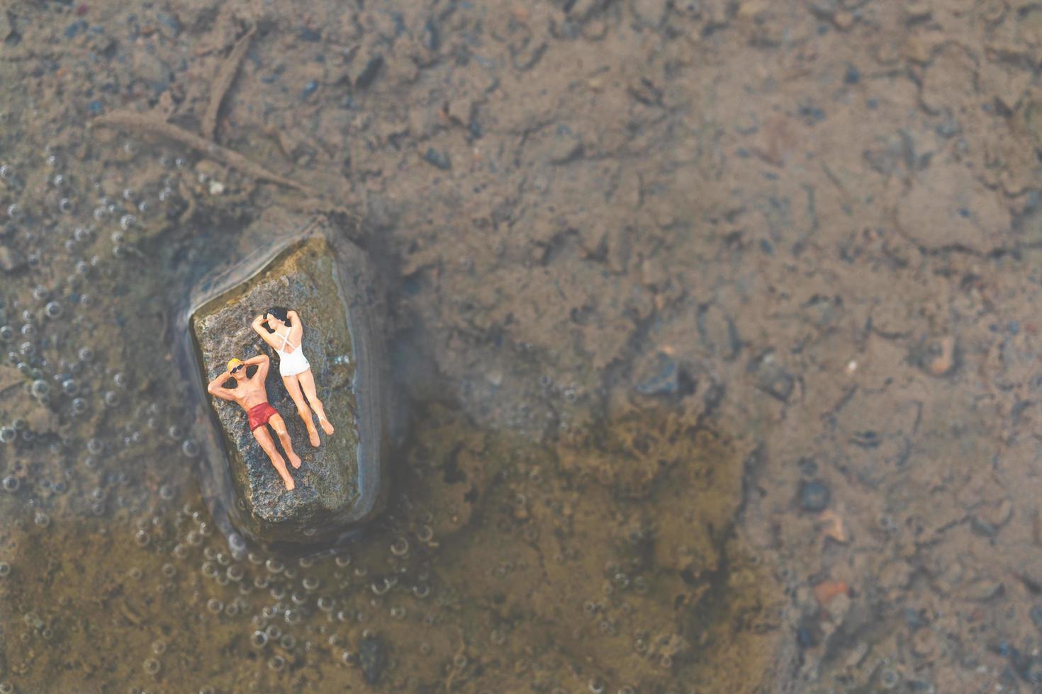 miniatyrfolk som bär baddräkter som kopplar av på en strand, sommarbegrepp foto