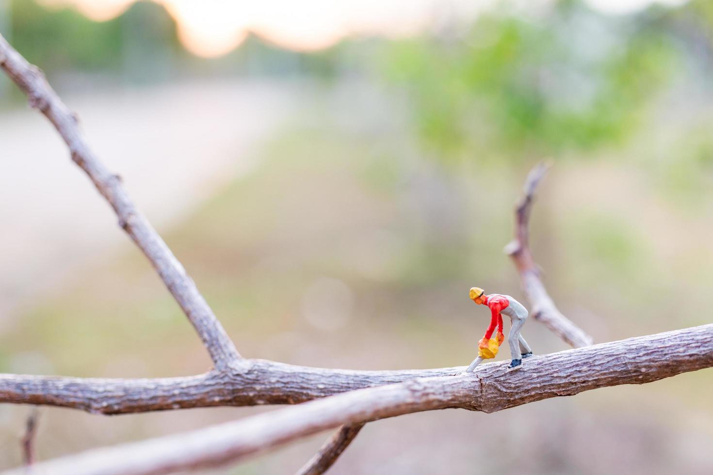 miniatyrarbetare som skär trädgrenar, avskogningskoncept foto