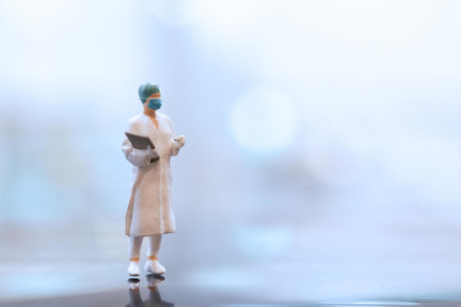 miniatyrläkare som bär en ansiktsmask under koronavirus och influensautbrott, virus och sjukdomsskyddskoncept foto
