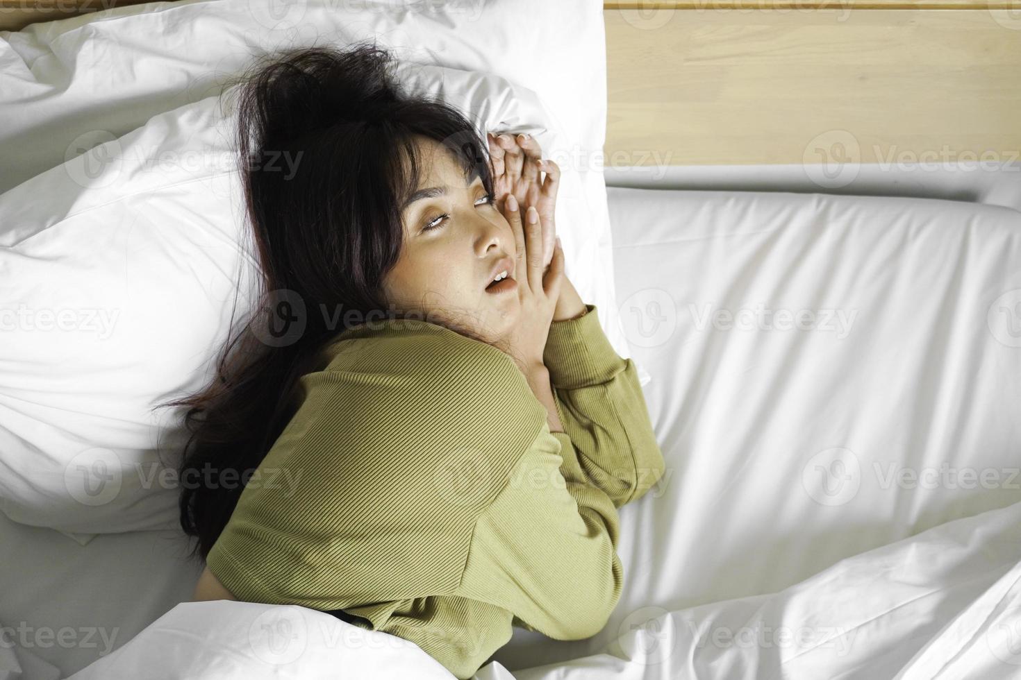 ung skön asiatisk kvinna sovande i henne säng och avkopplande i de morgon- foto