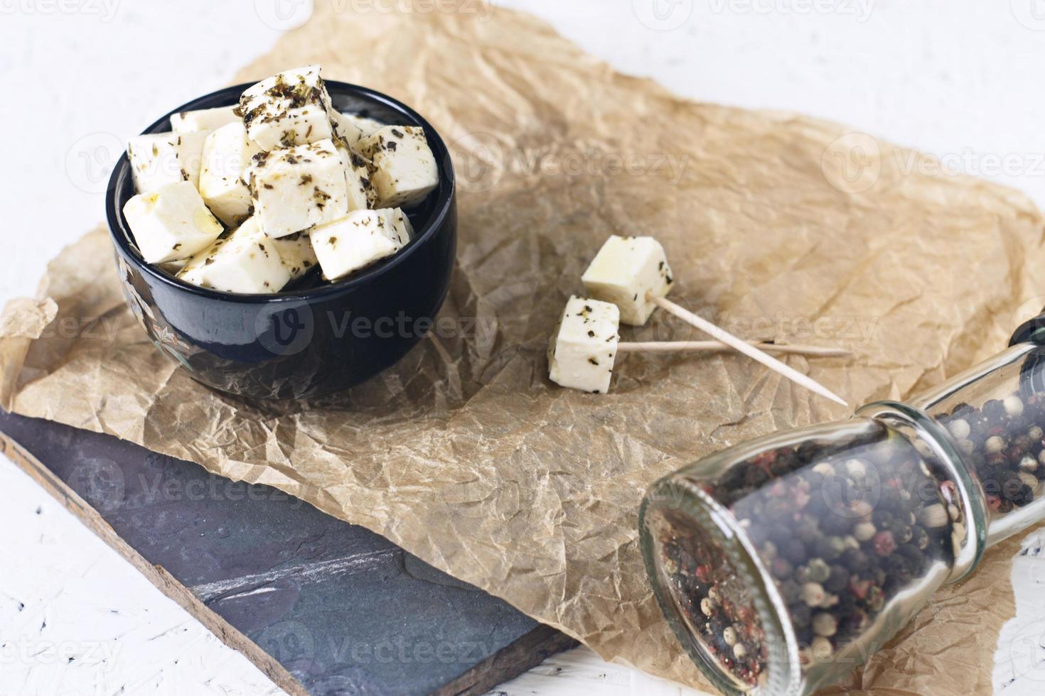 marinerad feta på en tallrik på en träskiva med kryddor på en vit bakgrund foto