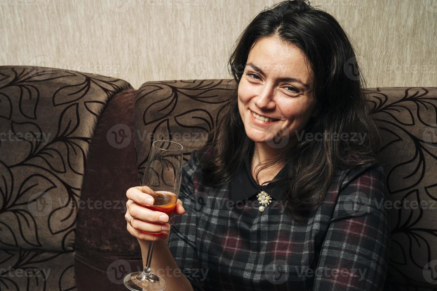 en ung kvinna innehar en glas av vit vin och utseende på de kamera foto