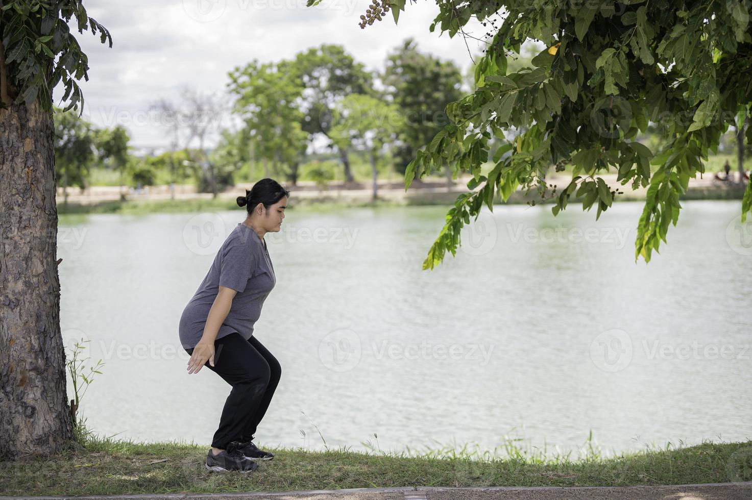 vacker asiatisk tjock kvinna spelar yoga i parken, behöver en slimmad kropp foto