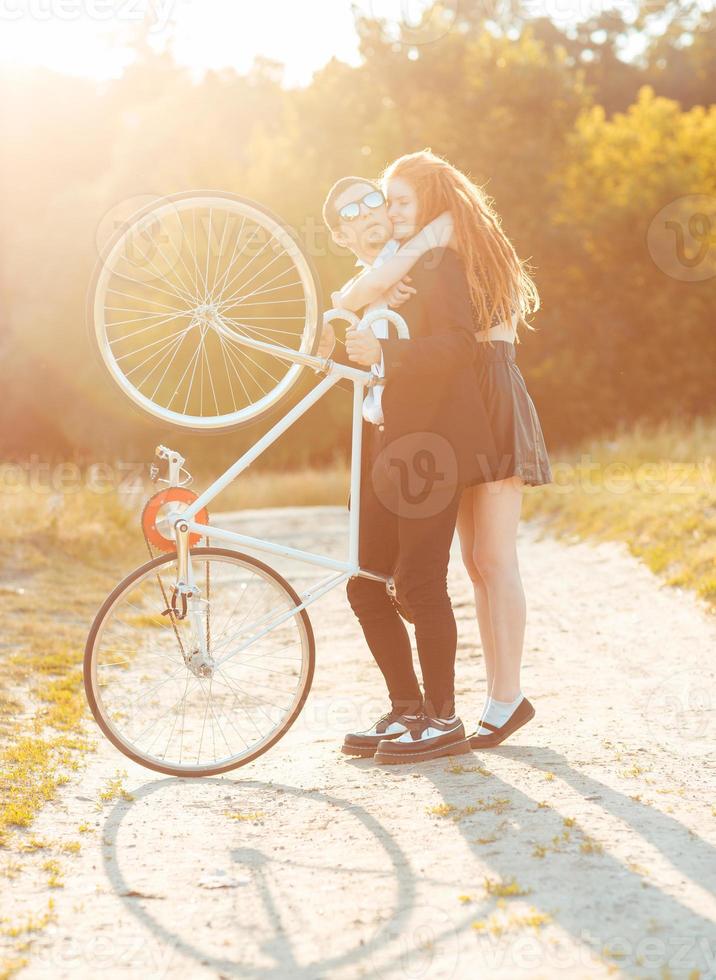 ung eleganta kille med flicka och de cykel utomhus foto