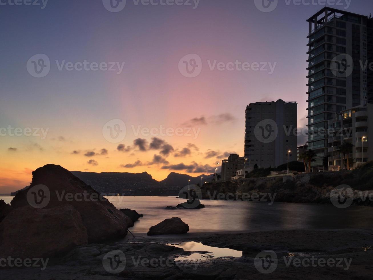 lägenhetstorn på en lugn strand vid solnedgången foto