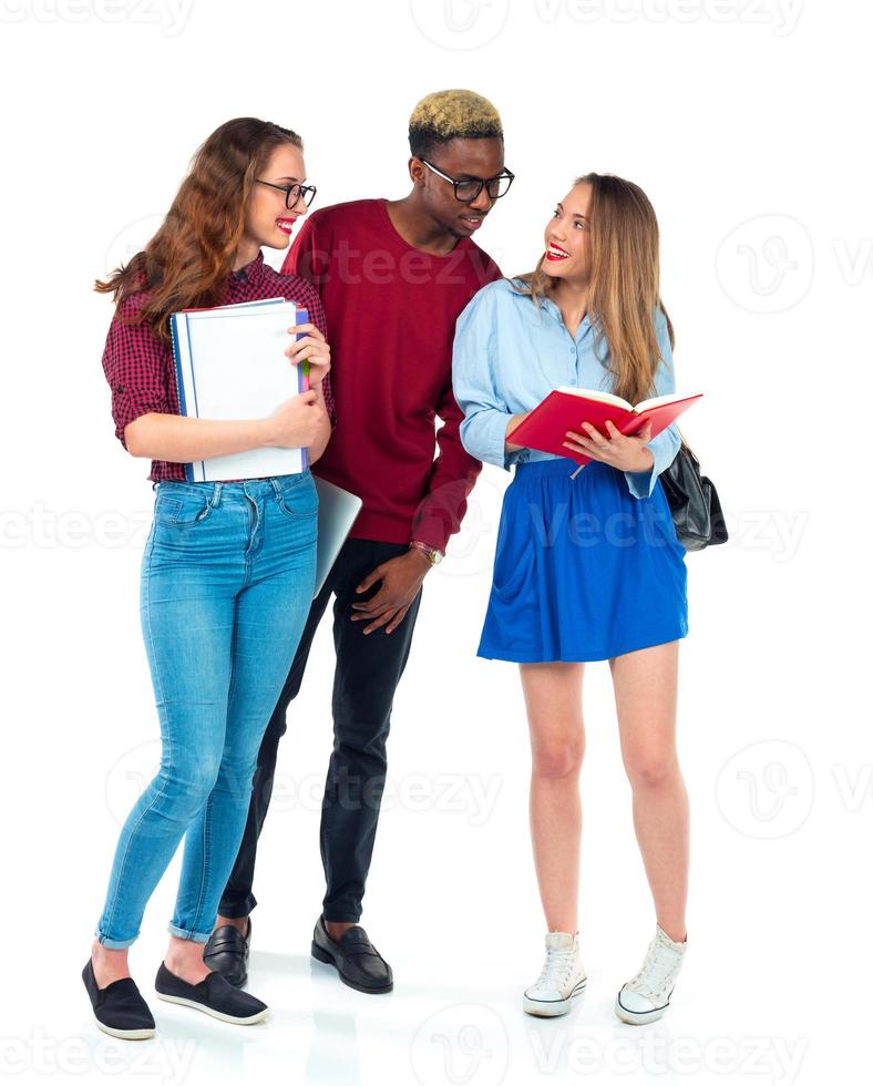 Lycklig studenter stående och leende med böcker, bärbar dator och påsar isolerat på vit foto