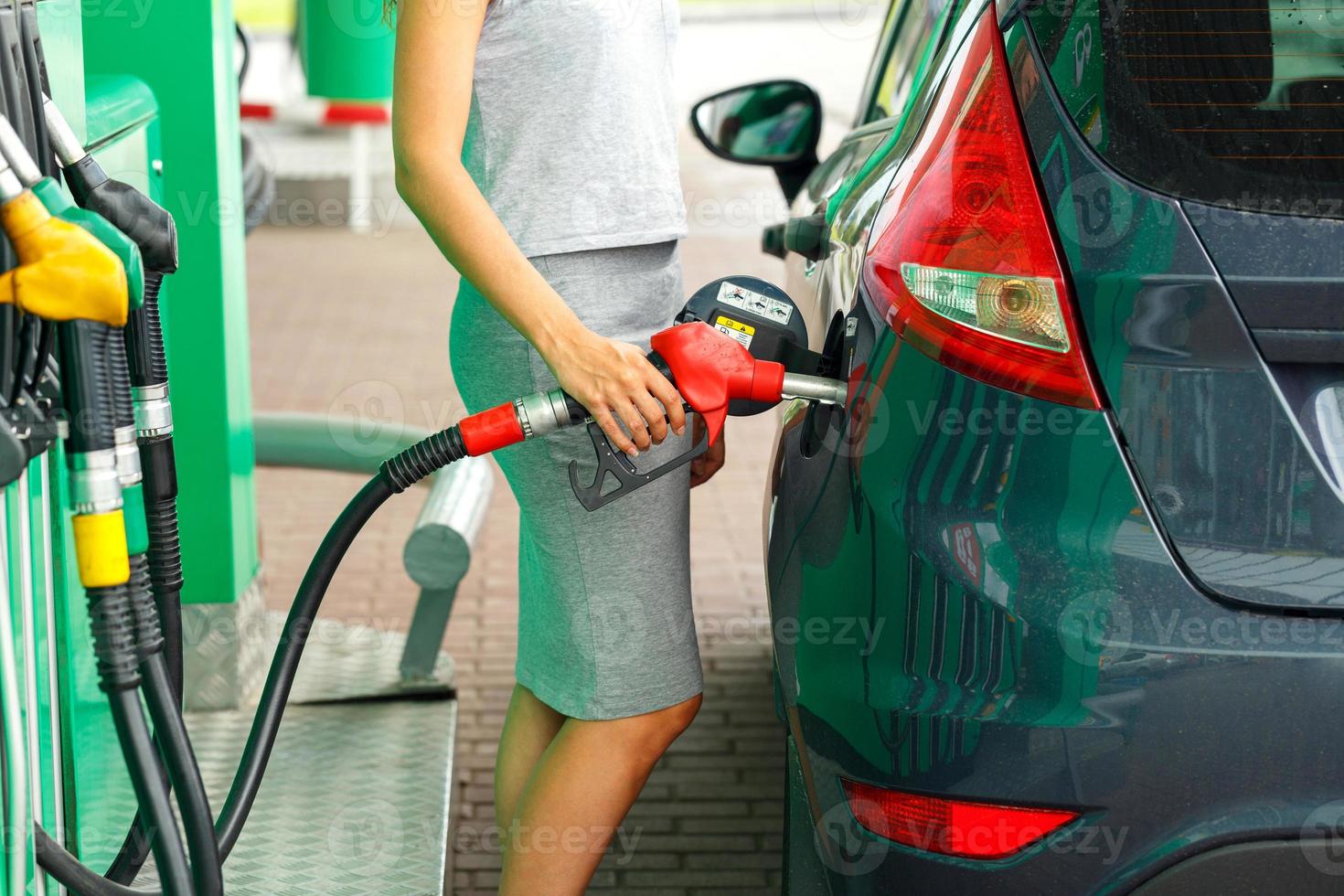 kvinna fyllningar bensin in i de bil på en gas station foto