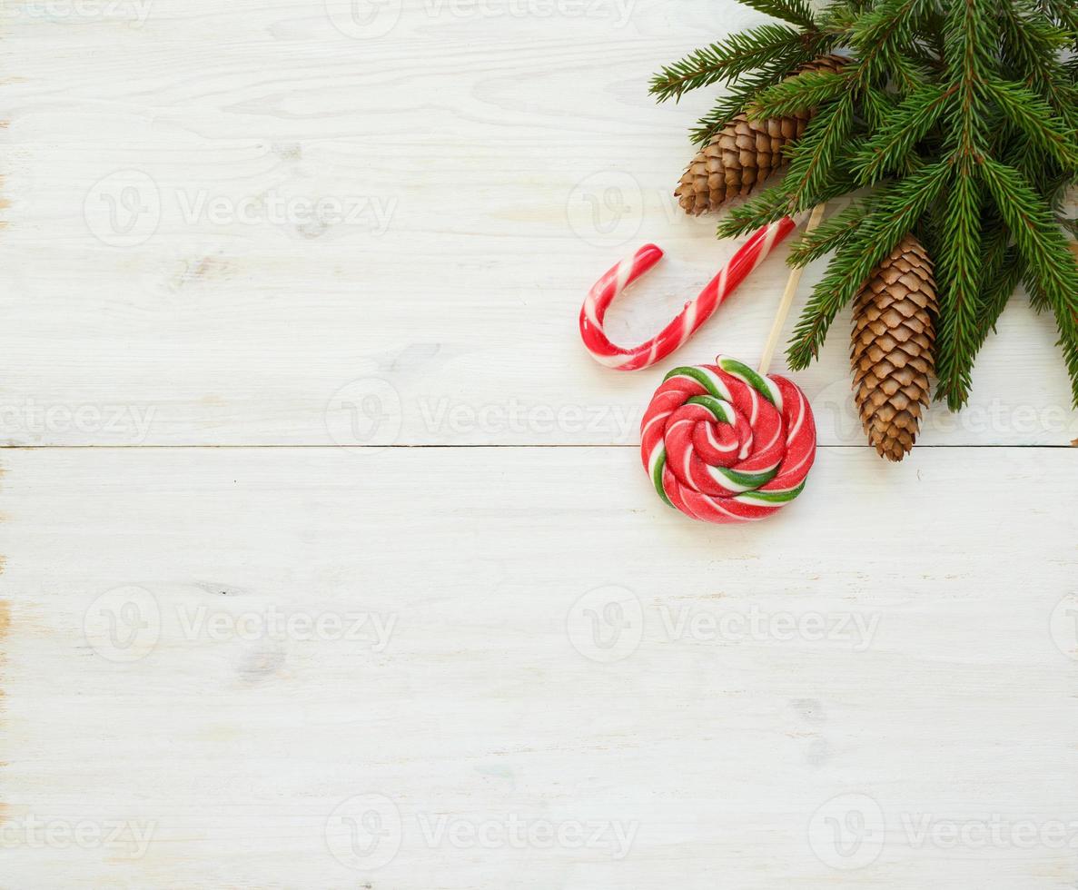 jul gräns med gran träd grenar med koner och godis sockerrör på vit trä- styrelser foto