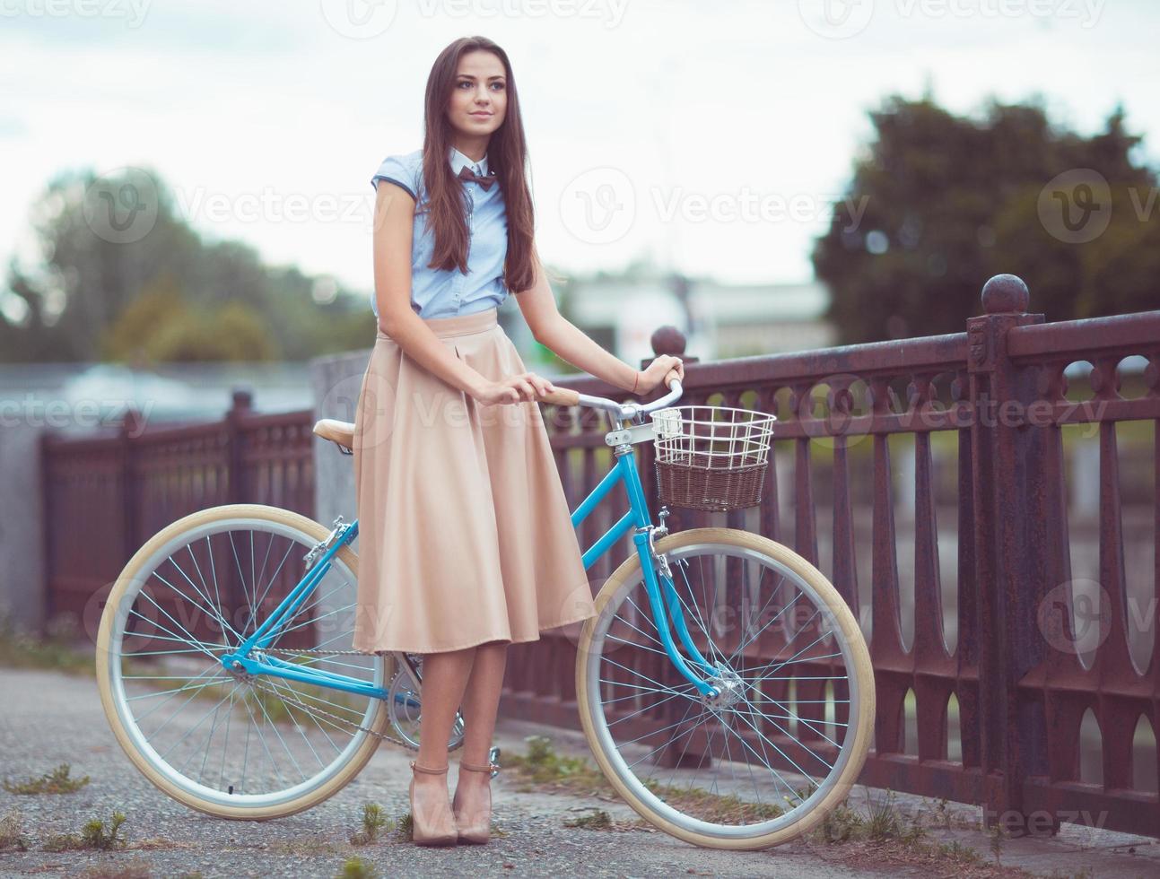 ung vacker, elegant klädd kvinna med cykel foto