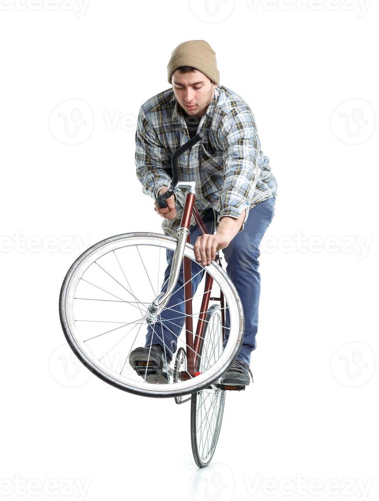 ung man håller på med knep på en cykel på en vit foto