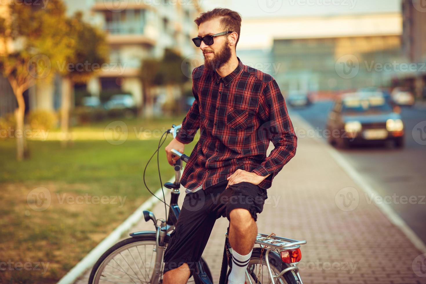 man i solglasögon ridning en cykel på stad gata foto