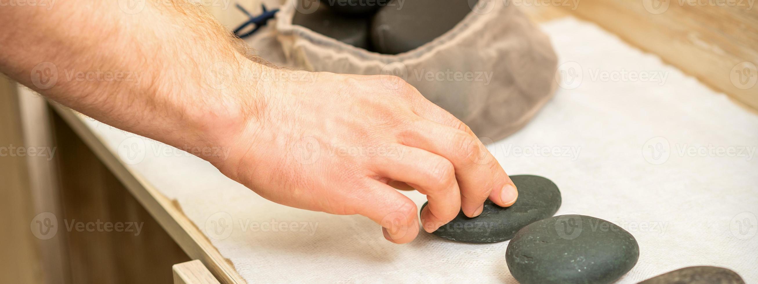 massör tar svart massage stenar foto