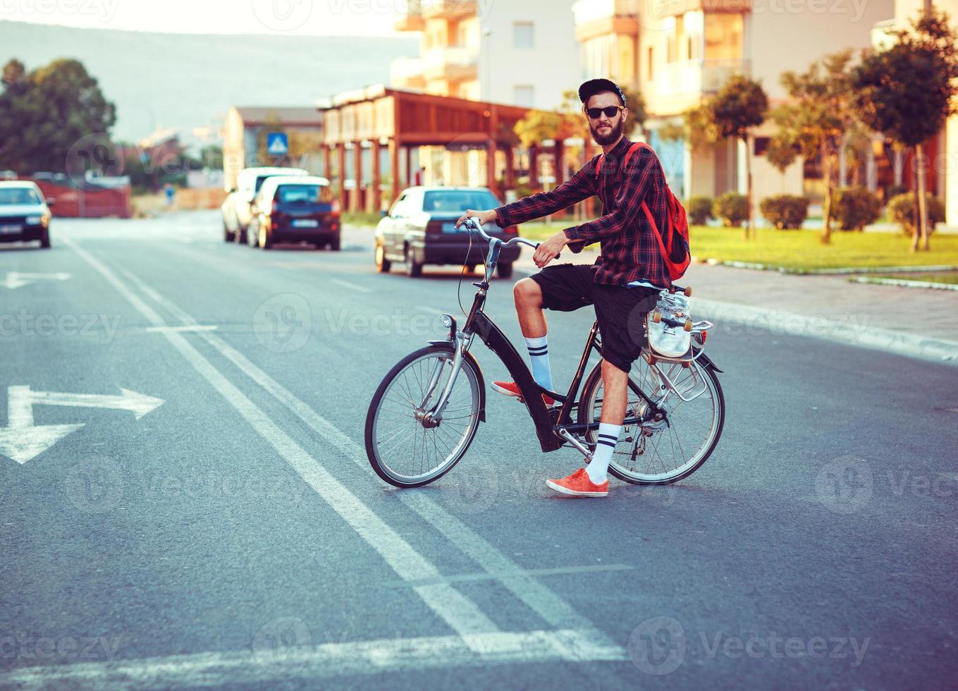 eleganta man i solglasögon ridning en cykel på stad gata foto