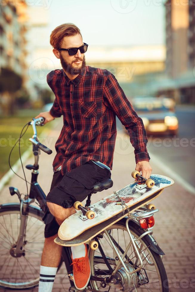 man i solglasögon ridning en cykel på stad gata foto