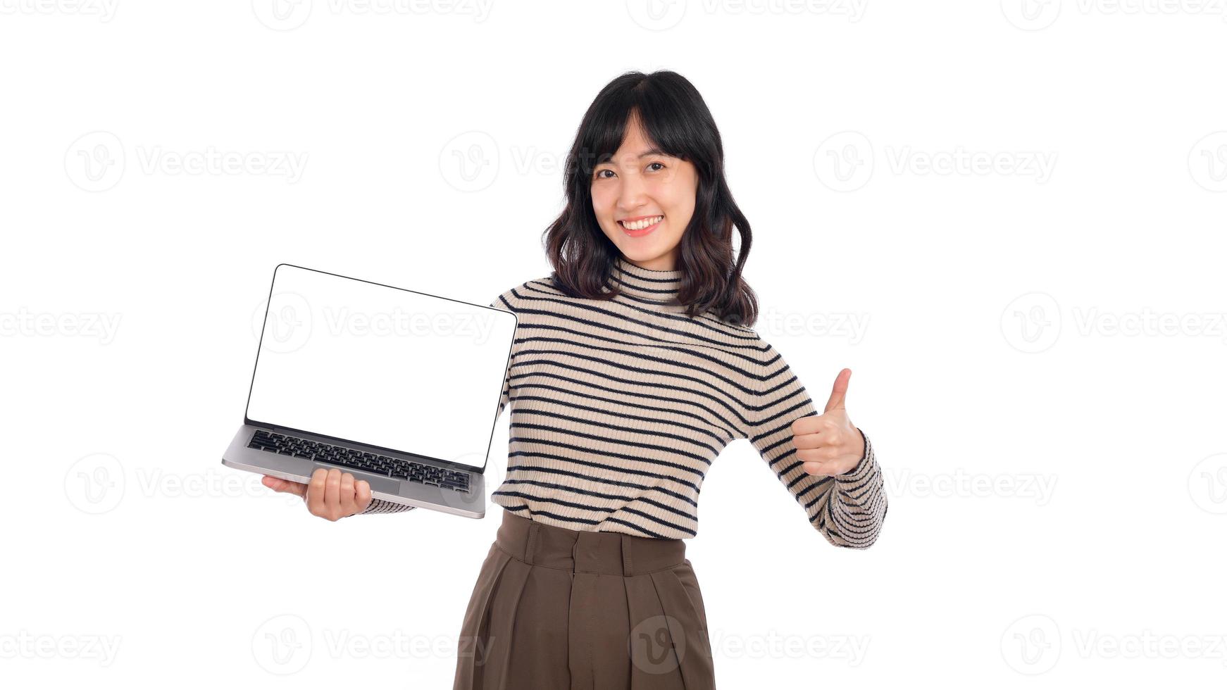 skön ung asiatisk kvinna på Tröja trasa innehav bärbar dator pc dator och ser på kamera med leende ansikte och tumme upp, isolerat på vit bakgrund foto