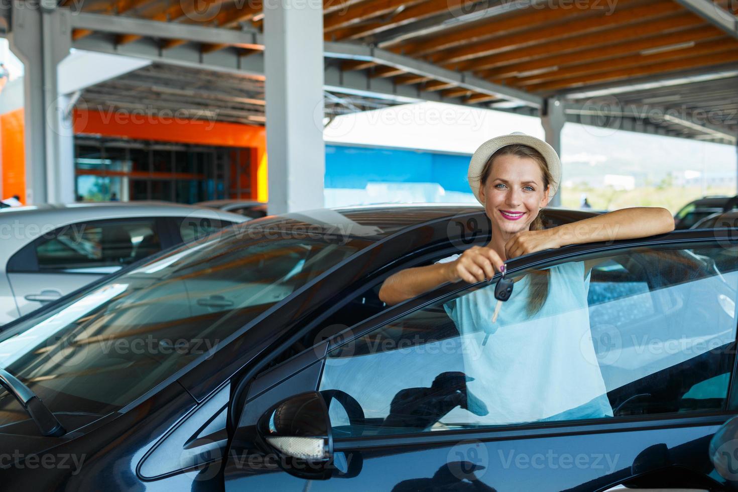 Lycklig kvinna stående nära en bil med nycklar i hand - begrepp av uppköp en Begagnade bil foto