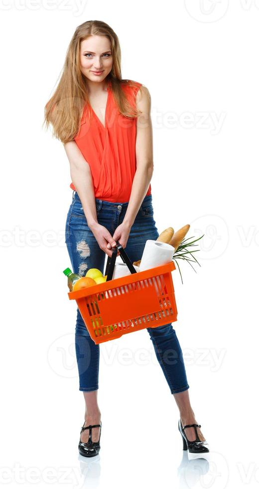 Lycklig ung kvinna innehav en korg full av friska mat på vit. handla foto