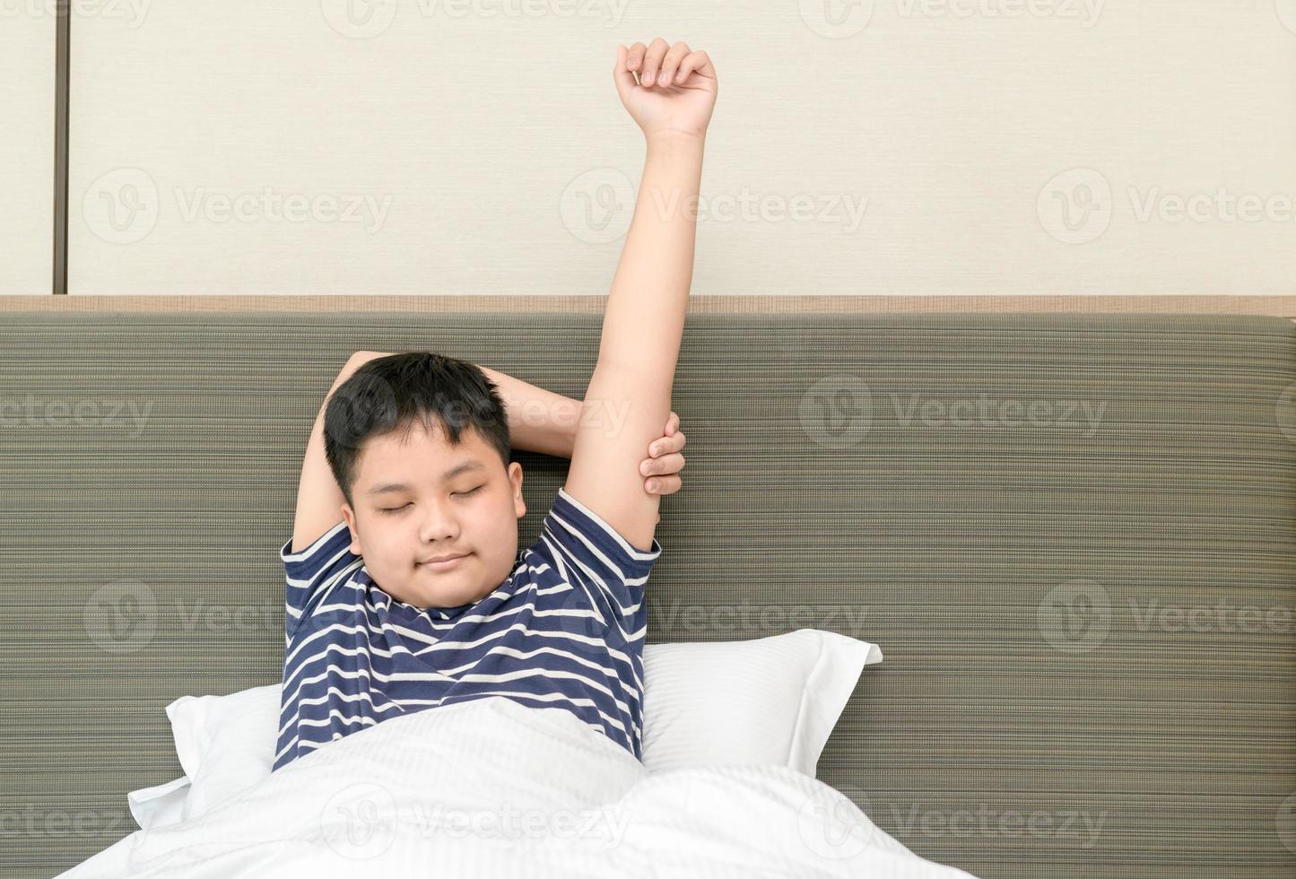 fet fett pojke vaknar upp och stretching på säng i morgon, Bra morgon- värld begrepp foto
