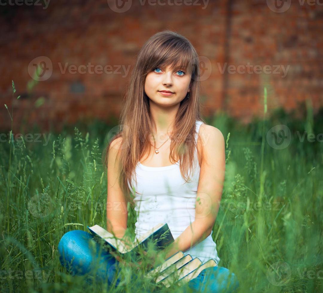 ung flicka med bok i de parkera på grön gräs foto
