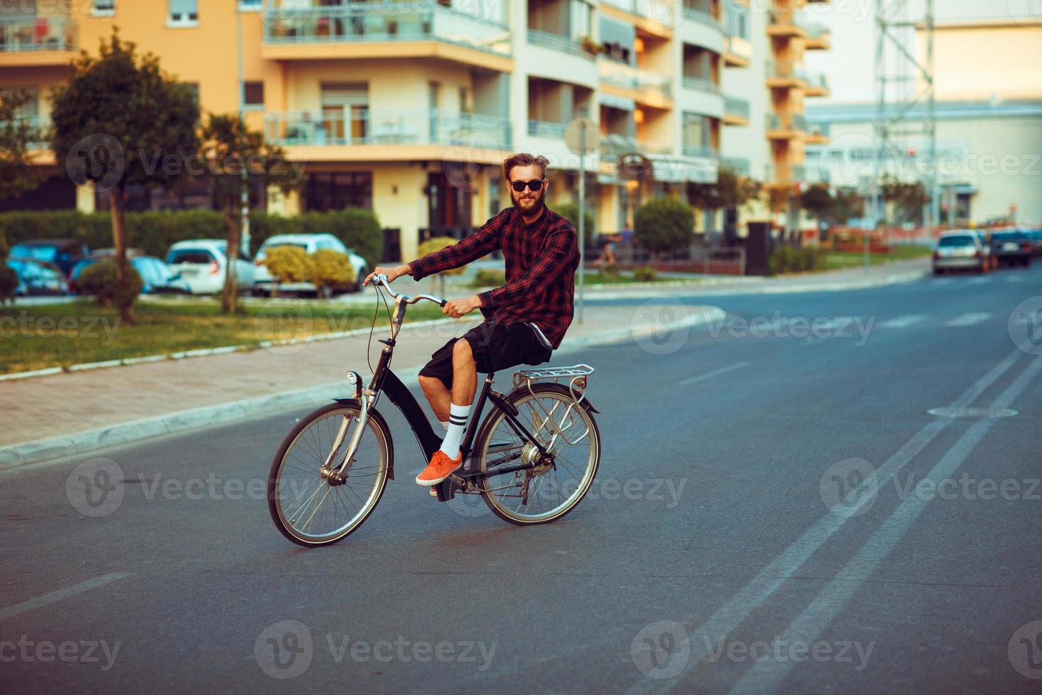 man i solglasögon ridning en cykel på stad gata foto