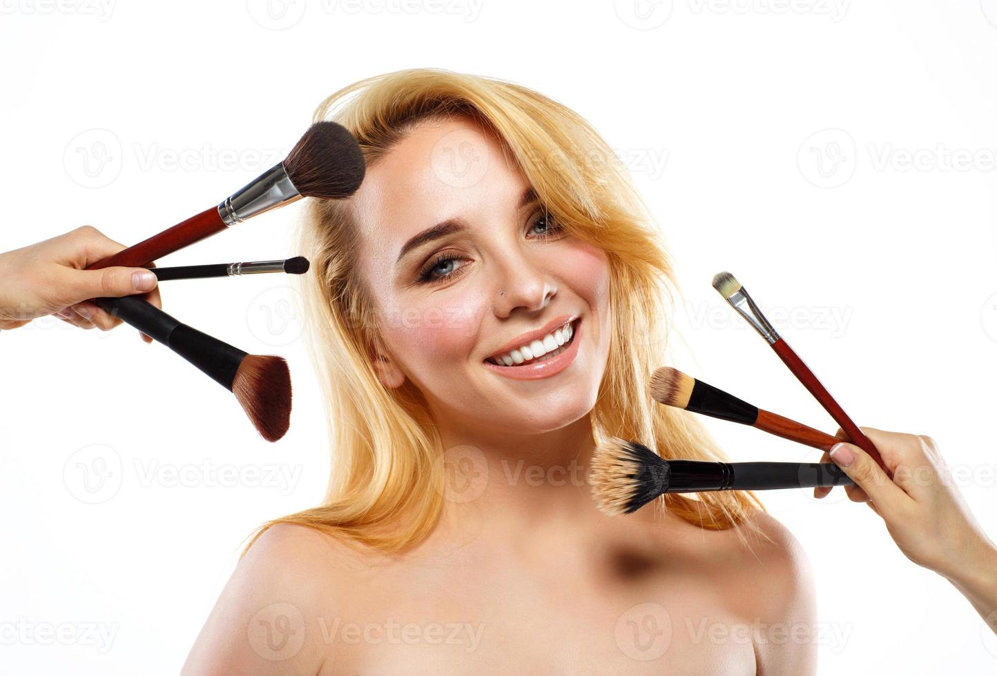 leende ung kvinna med smink borstar nära henne ansikte foto