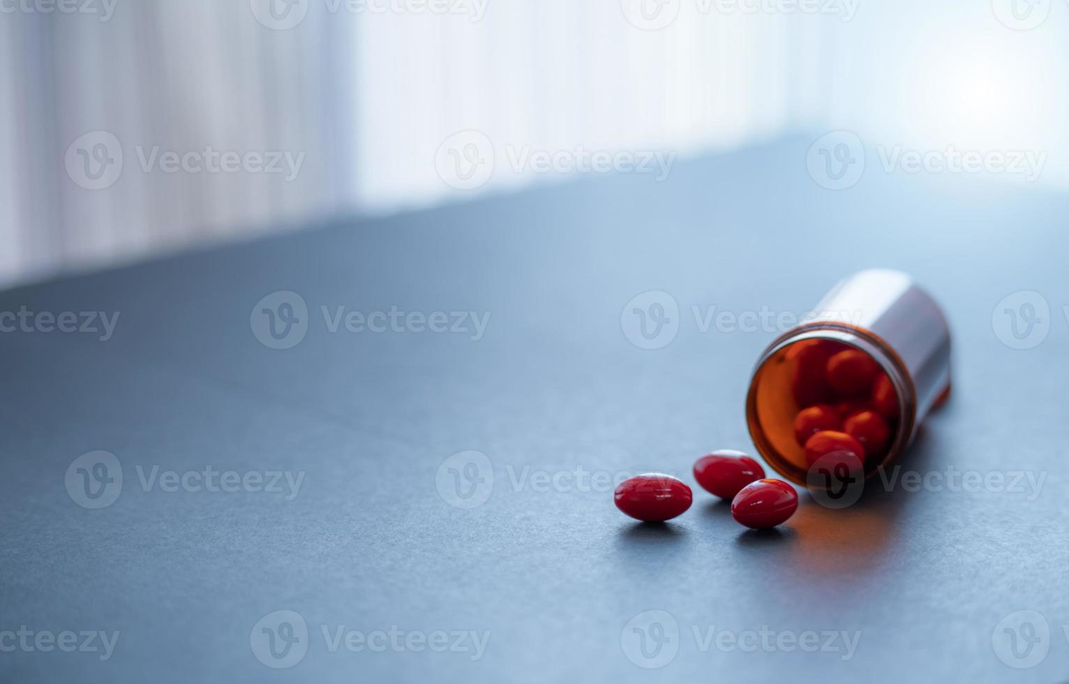 röd kapsel piller och brun plast läkemedel flaska. kodein och guaifenesin kapsel piller till lindra hosta. hosta medicin. opioider eller narkotika läkemedel. recept läkemedel. hosta undertryckande medicin. foto