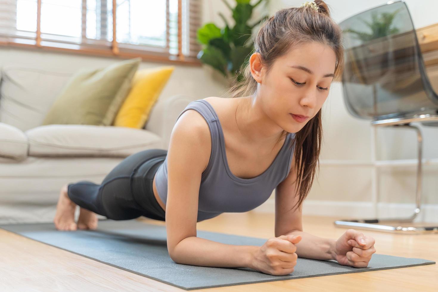 passa, sportig person asiatisk ung skön kvinna, flicka håller på med yoga utgör bordläggning och fysisk, Träning och öva stark på matta i levande rum. träna kondition övning människor i tillfällig ha på sig på Hem. foto