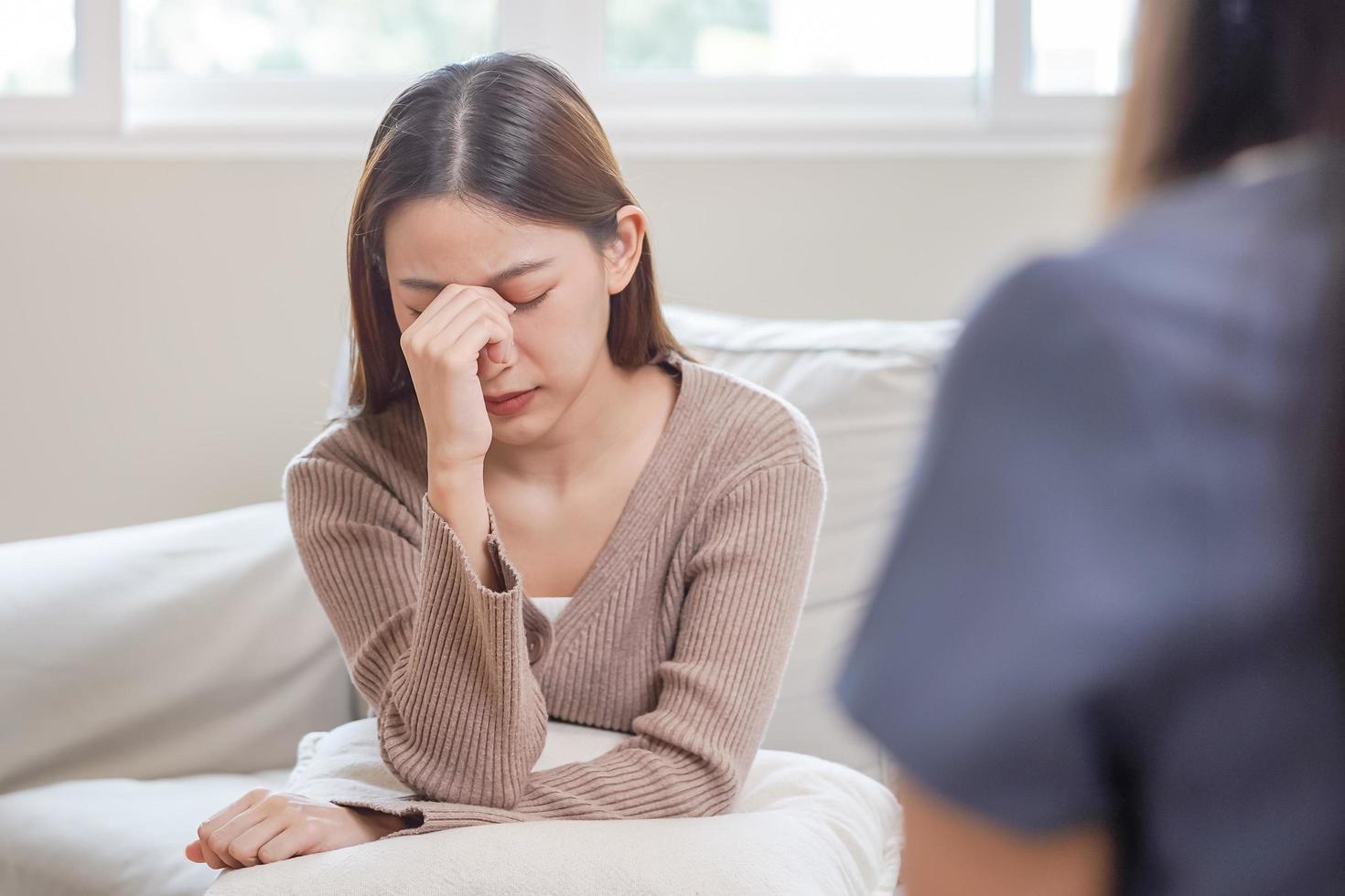 psykologi, depression. ledsen, lidande asiatisk ung kvinna hört med psykolog, psykiater medan patient rådgivning mental med läkare kvinna tar anteckningar på klinik. uppmuntrande, terapi. foto