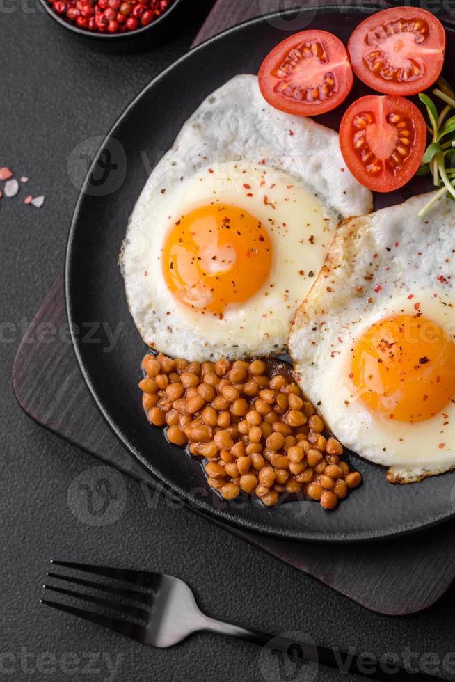 utsökt hjärtlig frukost bestående av två friterad ägg, konserverad linser och mikrogrönsaker foto