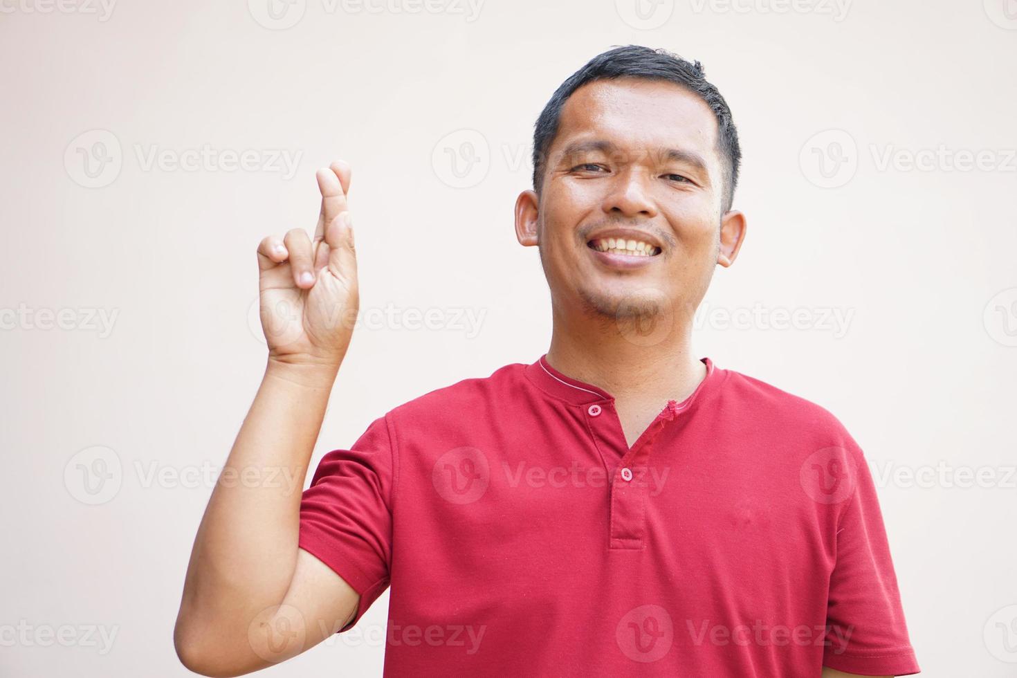 asiatisk man höjer händer med fingrar korsade foto