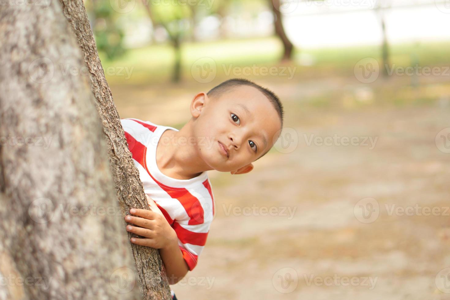 en pojke döljer Bakom en träd så hans mor kan inte ser foto